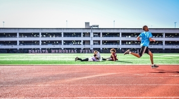 Male student running track while 2 other students study