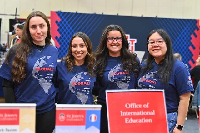 4 members standing at the Office of International Education table