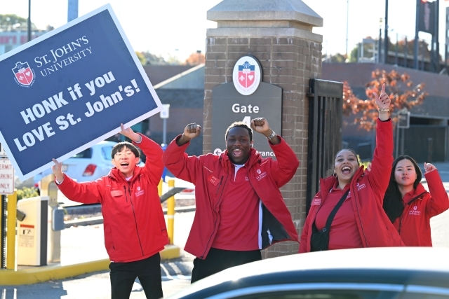 St. John's Orientation Leadres hodling a sign on Union Tpke that reads, "Honk if you LOVE St. John's"